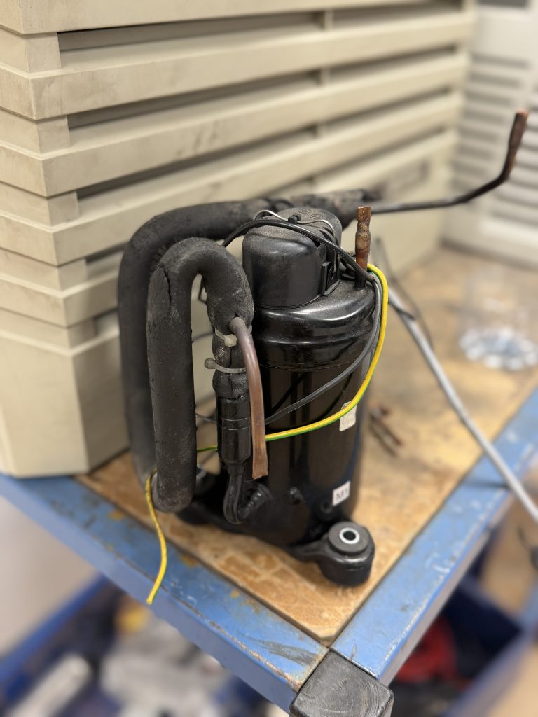 Compresseur déposé d’un climatiseur d’armoire électrique en atelier